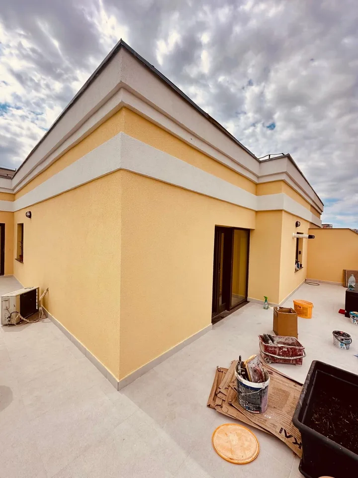 Terasă circulabilă cu plăci, lângă fațada galbenă cu profile decorative albe, Iași